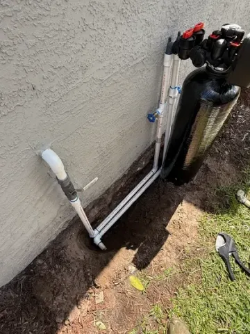 A water filter is being installed on the side of a house.
