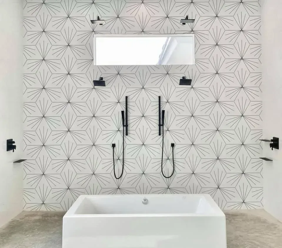 Remodeled bathroom with a freestanding tub, two matte black handheld showers and geometric wall tile