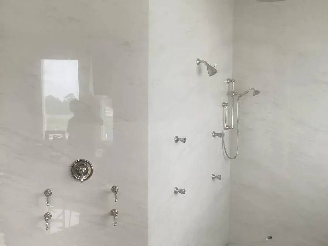 Shower wall fitted with a showerhead, handheld sprayer on a slide bar, body spray jets and valve trim
