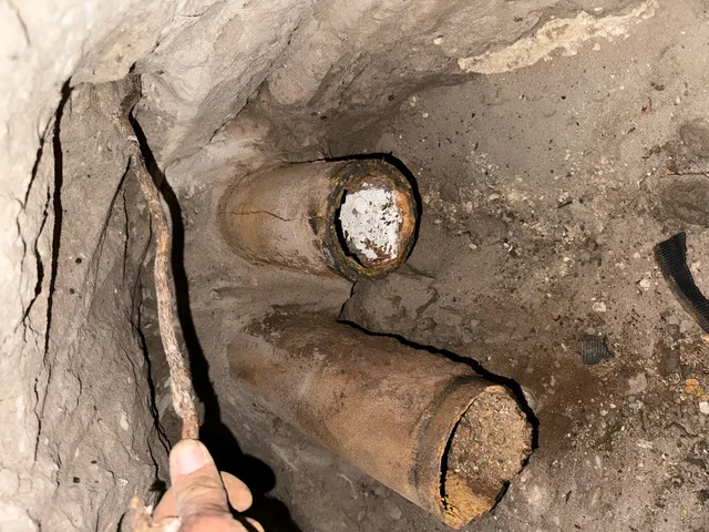A person is holding a stick in a hole in the ground.